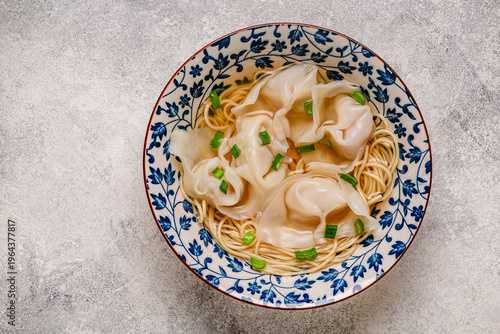 Noodles and dumplings wontons in bowl with green onions