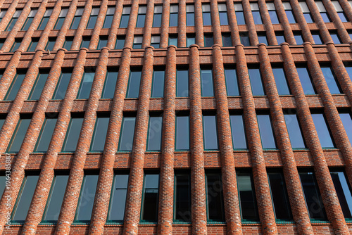 HAMBURG, GERMANY - MARCH 07, 2026: Full frame texture of a modern red brick office building facade with vertical columns and glass windows