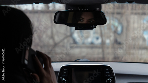 Bilde på lerret Woman driver talking on the phone behind the wheel of a parked car