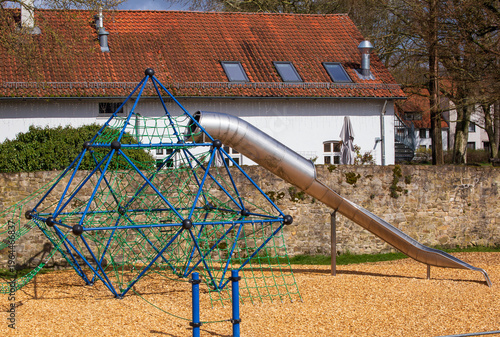 Children's playground with climbing frame and slide in bright daylight
