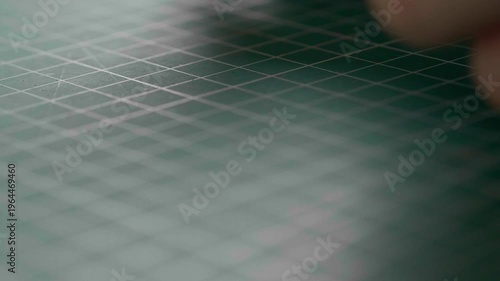 A very detailed close-up of a craftsman making a genuine brown leather item, perhaps a wallet or a key holder. He's just glued two pieces together and is pressing them together with his fingers.