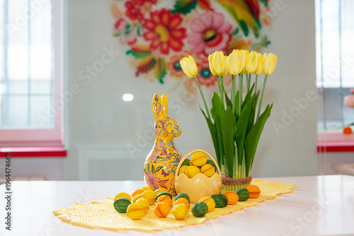 A porcelain basket with baked filled nuts against a background of a vase of yellow tulips and an Easter bunny