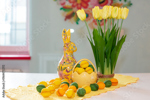 A porcelain basket with baked filled nuts against a background of a vase of yellow tulips and an Easter bunny