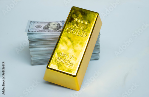 Gold bar and pile money banknote 100 USD on a gray background
