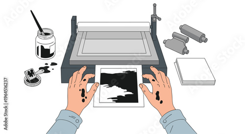 An overhead view shows two ink-stained hands holding a freshly printed abstract black and white image, just removed from a printing press, with an ink pot, brush, and blank papers nearby.