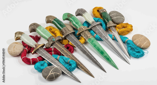 Seven ornate daggers with green, white, and silver handles, alongside yarn and smooth stones