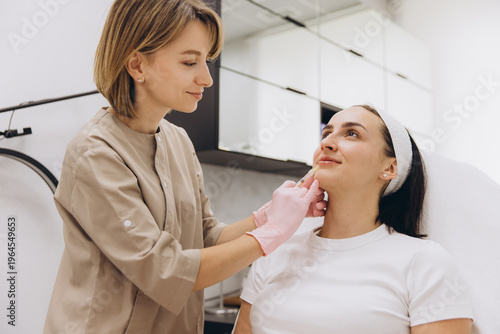 Foto Beautician injecting a filler into a woman's chin and jawline, enhancing facial
