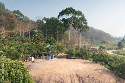 Serene rural scene featuring rolling hills, lush greenery and simple countryside dwelling. Vacant land plot prepared through soil backfilling for future house construction or property development.