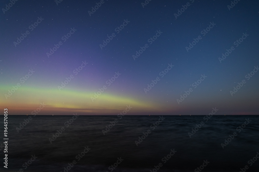 Fototapeta premium Aurora borealis dances over the Baltic Sea in Poland under a starry sky