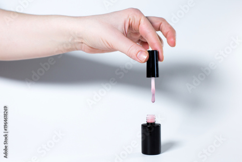Canvastavla Black nail polish bottle with hand isolated on white background, copy space template