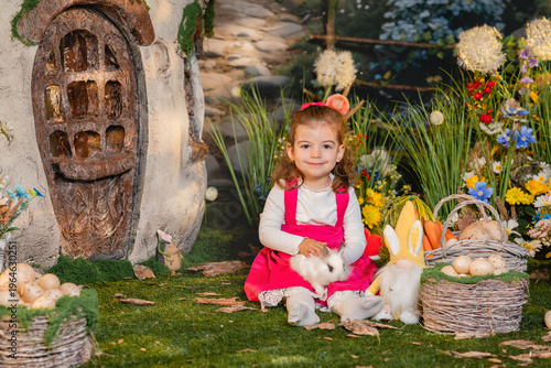 little girl sitting in spring garden with bunny and easter eggs surrounded by flowers, magical fairytale scene with bright colors and happy mood