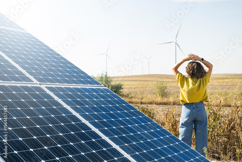 Wallpaper Mural Rear view of a woman observing wind turbines. Solar panel in the foreground Torontodigital.ca
