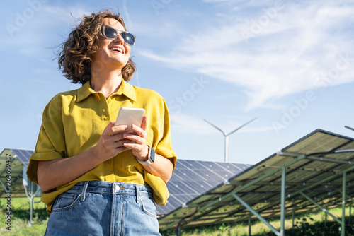 Wallpaper Mural Woman with smartphone at clean energy site solar and wind power farm Torontodigital.ca
