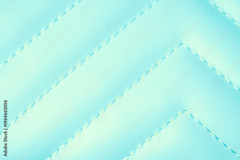 Fototapeta premium Detailed view of vibrant light blue quilted leather texture with intricate zigzag stitching surface