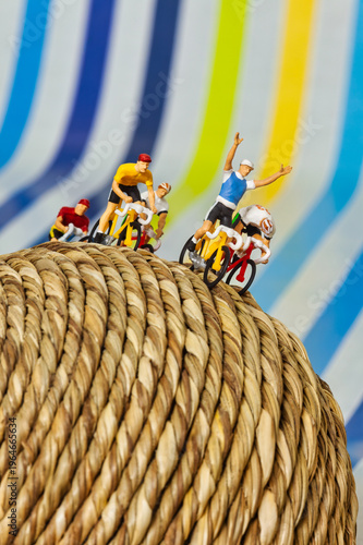 Winning Miniature Cyclists Racing Toward Success on a Woven Sphere symbolizing achievement and competitive leadership