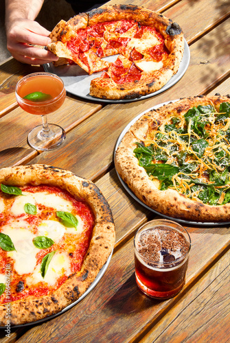 outdoor sunny setting with three pizzas and cocktails