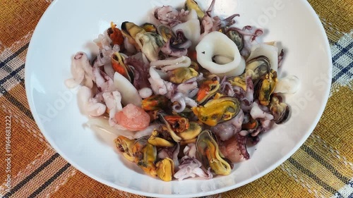 Mix of boiled seafoods in white bowl on checkered tablecloth