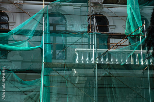Building facade under renovation with green safety netting
