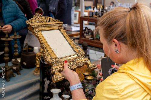 Fotografía A woman examines an ornate vintage mirror among assorted antiques and porcelain