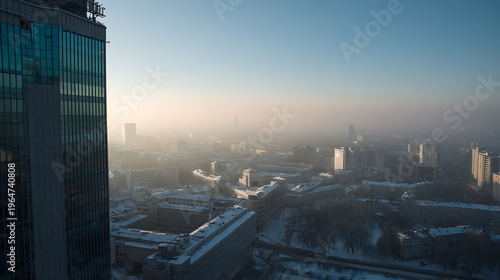Winter city aerial view with modern skyscraper facade, cold atmosphere, urban landscape covered in snow and haze during a clear sky day