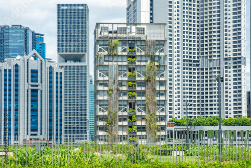 Photography Modern building with vertical greenery facade surrounded by skyscrapers in Kuala Lumpur city, Malaysia