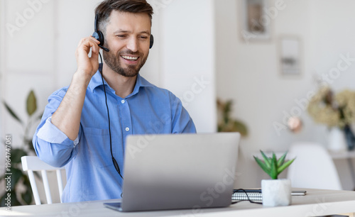 Hotline Operator. Handsome Man Customer Support Manager In Headset Working With Laptop Computer In Office, Consulting Clients Online, Managing Issues, Sitting At Desk, Free Space