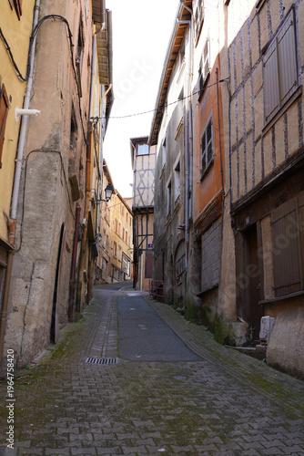 Historic narrow cobblestone alley with medieval half-timbered houses in Thiers, France