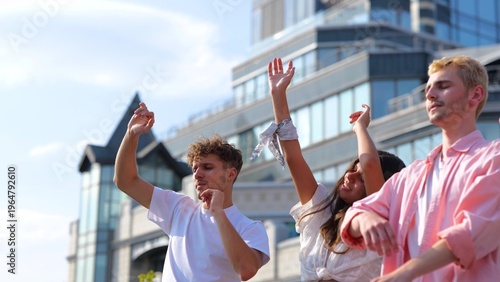 Many young Caucasian men and women dancing in positive mood and jumping to music outdoors on summer day party. Close up. Beautiful carefree people having fun together