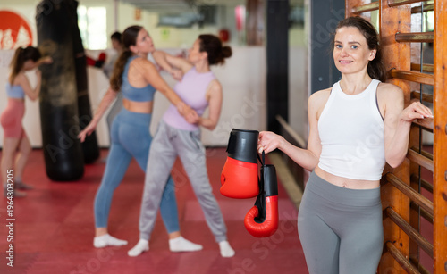 Woman athlete with boxing gloves pose before training in gym, female sport team leader during students workout process. Coaching staff of school of box and self defense