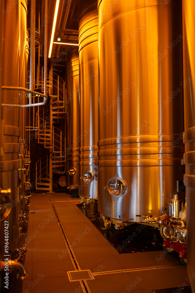 Fototapeta premium Visit of modern underground caves with steel tanks for fermentation and oak barrels for aging og wine, traditional method making champagne sparkling wine in Reims, Champagne, France