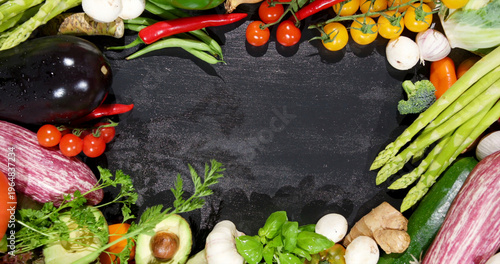 Fresh vegetables are arranged in a circular pattern on a dark surface ready for cooking or display purposes