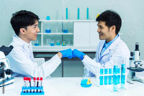 Two asian scientist men fist bump team partner shake hands together. Teamwork Men science chemistry research working success in laboratory. Close up hand pharmaceutical science corporate partnership