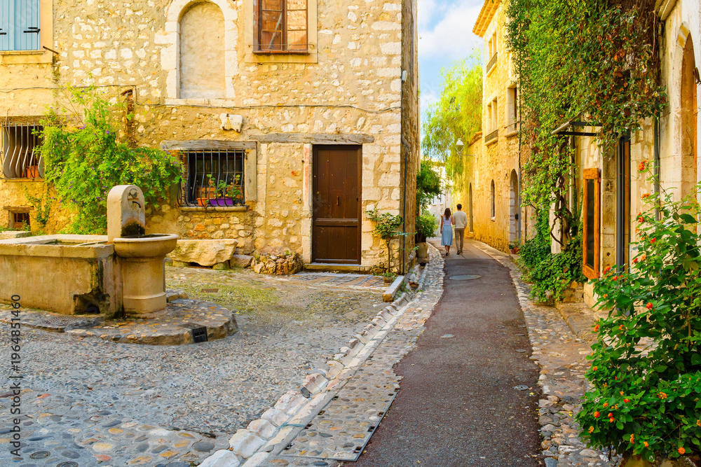 Obraz premium A small cobblestone square with a traditional water fountain in the preserved medieval hilltop village of Saint-Paul-de-Vence, located in the Provence-Alpes-Côte d'Azur region of southeastern France.