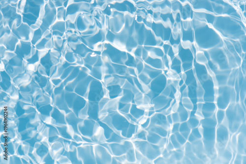 Blue water with ripples on the surface. Defocus blurred transparent blue colored clear calm water surface texture with splashes and bubbles. Water waves with shining pattern texture background.