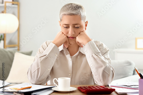 Sad mature woman in debt at...