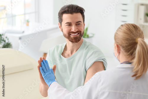 Smiling man receiving vacci...