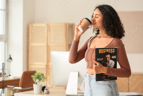 Beautiful young African-American businesswoman with paper cup of hot coffee a...