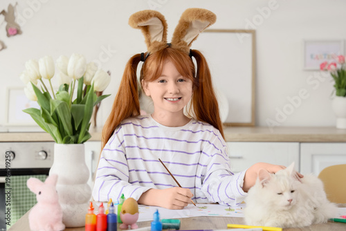 Tableau sur toile Cute girl with adorable cat and bunny ears painting at home