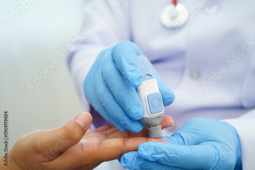 Doctor check diabetes from finger blood sugar level with digital glucose monitor measure and test stripe.