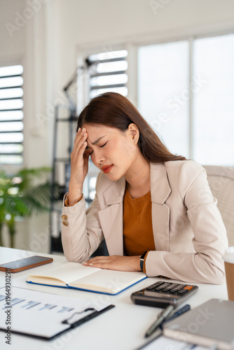 Young asian business woman feeling stress and tired from work sitting on the chair about constant headaches a migraine of working hard at office.