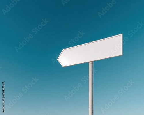Blank direction sign against a clear blue sky
