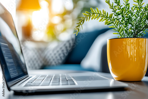 Laptop on table beside vibrant potted plant, creating cozy workspace atmosphere filled with natural light and greenery
