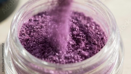 Purple powder explosion forming abstract vibrant pattern concept. Close up of vibrant purple cosmetic powder in a glass jar for makeup and beauty products