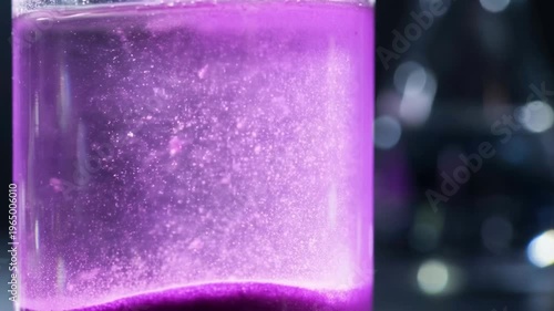 Purple powder explosion forming abstract vibrant pattern concept. Close up of vibrant purple liquid with sparkling particles suspended in a transparent glass container