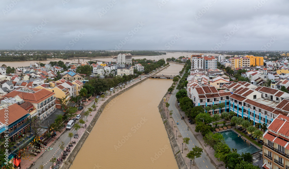 Fototapeta premium Aerial view of the Thu Bon River flowing through Hoi An Ancient Town, Vietnam. The river is high and muddy due to seasonal flooding in Quang Nam Province.