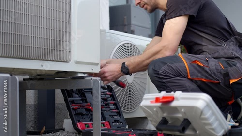 Technician servicing outdoor heat pump unit with tools beside residential house. Concept of HVAC maintenance home climate control and energy efficient heating and cooling