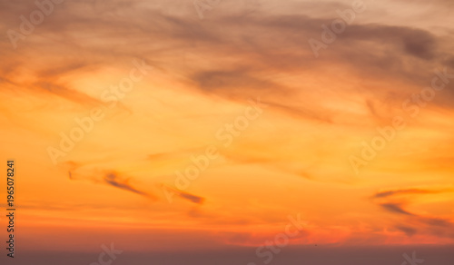 Orange and pink sunset sky with soft glowing clouds. Warm golden gradient background with smooth pastel tones and tranquil evening atmosphere. Natural abstract sky texture