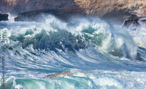 Powerful ocean waves crashing under a clear blue sky. Dynamic seascape with rolling surf, sea foam and energy of moving water, capturing the raw force and beauty of nature in motion