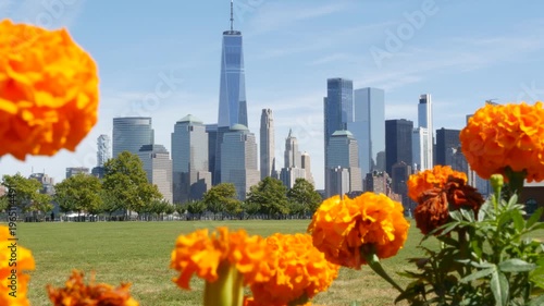 New York City Manhattan Downtown Financial District skyline, World Trade Center tower from New Jersey Liberty state park, United States. Green grass lawn, flowers and skyscraper buildings cityscape.