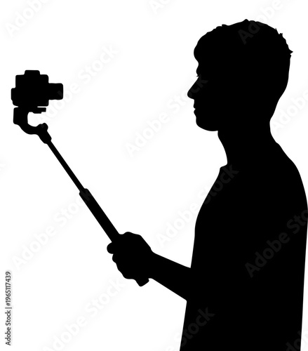 Silhouette of a young man using a gimbal stabilizer and selfie stick to record video for social media or vlogging